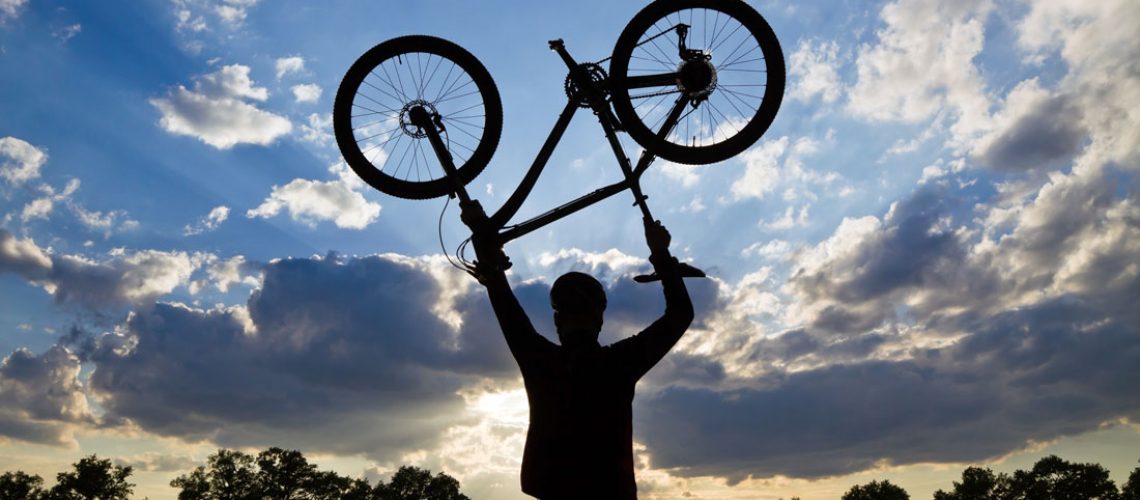 man holding bicycle overhead