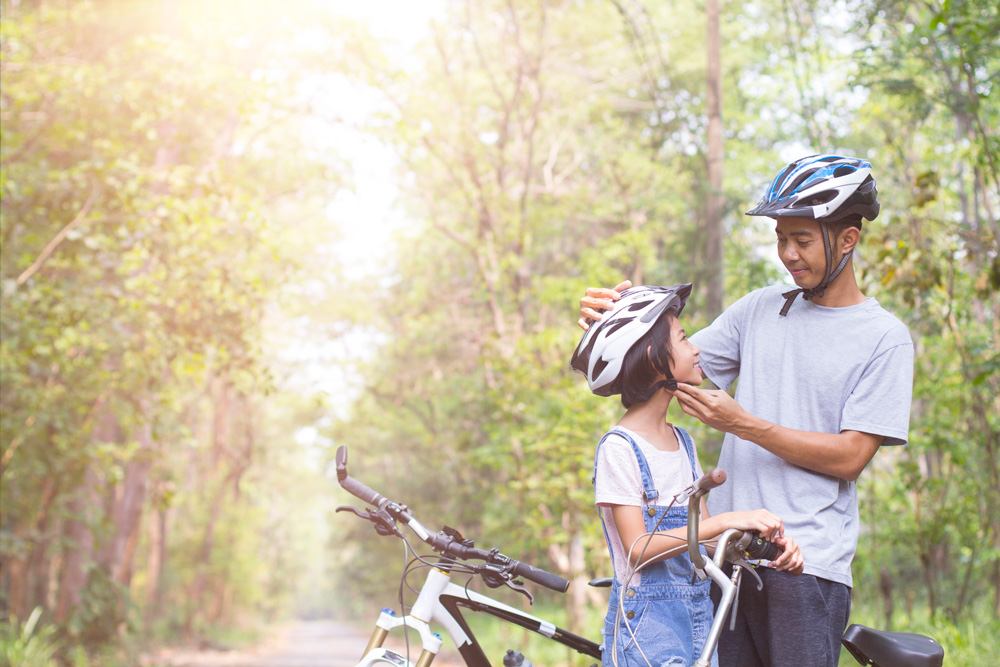 father and daughter enjoying a bike ride while wearing helmets
