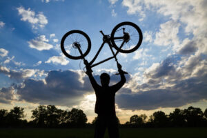 man holding bicycle overhead